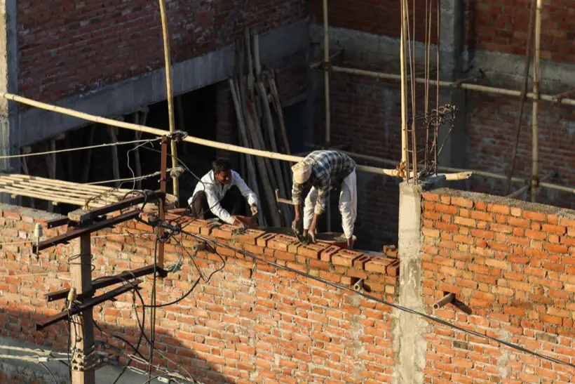 Bricklayers building a brick wall on scaffolding